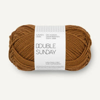 Ball of mustard brown yarn with a label on a white background