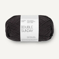 Ball of darkest grey yarn with a label on a white background