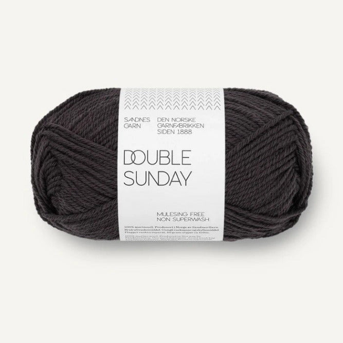 Ball of darkest grey yarn with a label on a white background