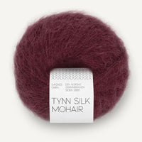 Ball of burgundy Tynn Silk Mohair yarn with a label on a white background