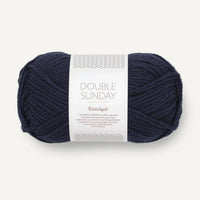Ball of deep navy blue yarn with a label on a white background