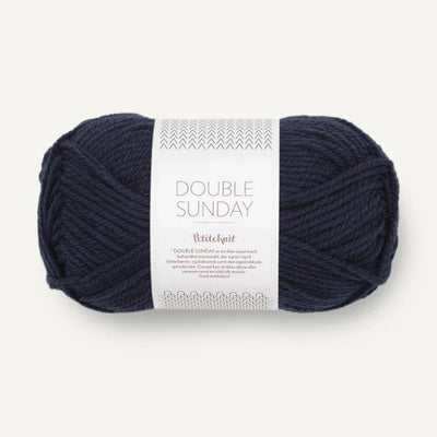 Ball of deep navy blue yarn with a label on a white background