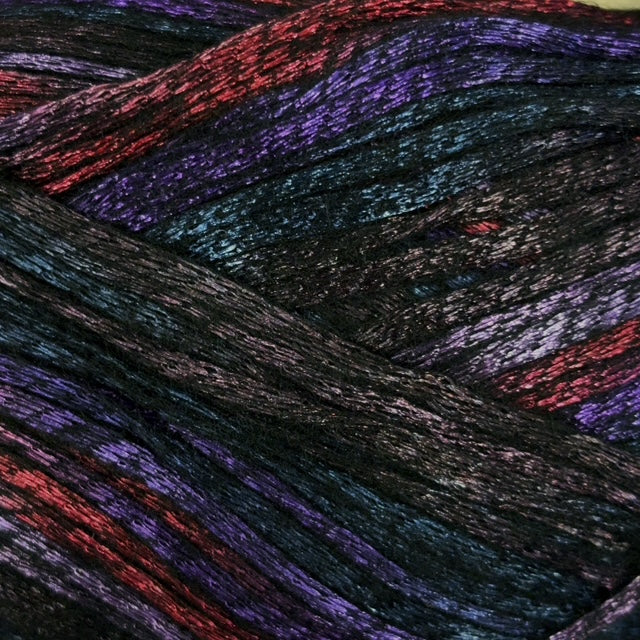Close-up of variegated yarn strands in a dark base with shimmering purple, red, and blue metallic highlights.