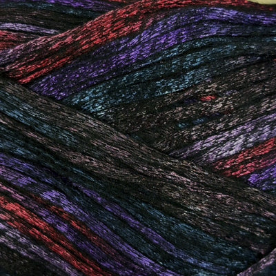 Close-up of variegated yarn strands in a dark base with shimmering purple, red, and blue metallic highlights.