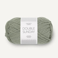 Ball of sage green yarn with a label on a white background