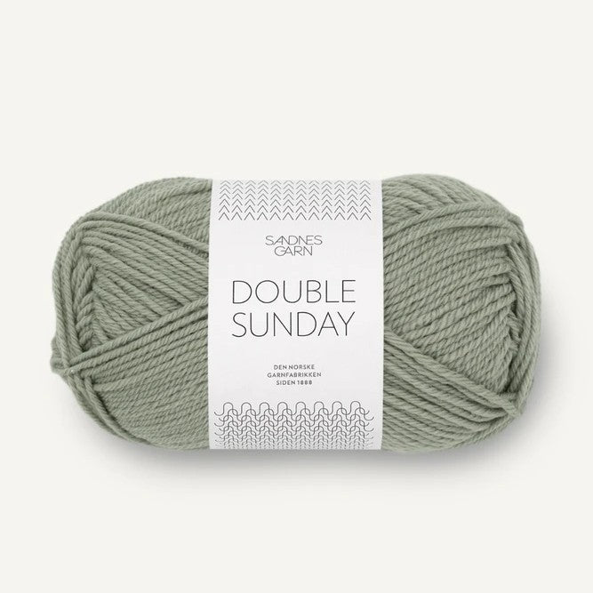 Ball of sage green yarn with a label on a white background