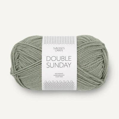 Ball of sage green yarn with a label on a white background