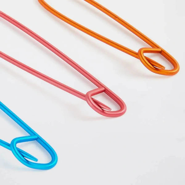 Three colorful stitch holders (orange, pink, blue) on a white background