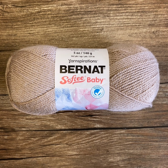 Ball of tan coloured Bernat Softee Baby yarn on a wooden surface
