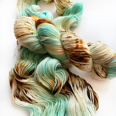 Multicolored yarn skein and loose yarn in mint and brown together on a white background