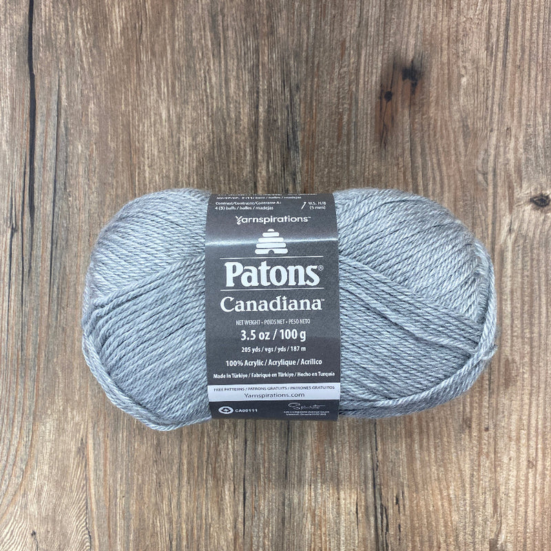 Ball of grey yarn with a dark grey label on a wood background
