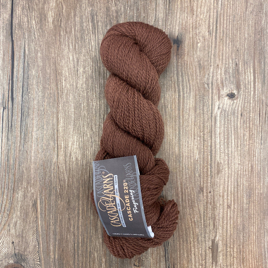 Brown skein of yarn with a label on a wooden surface
