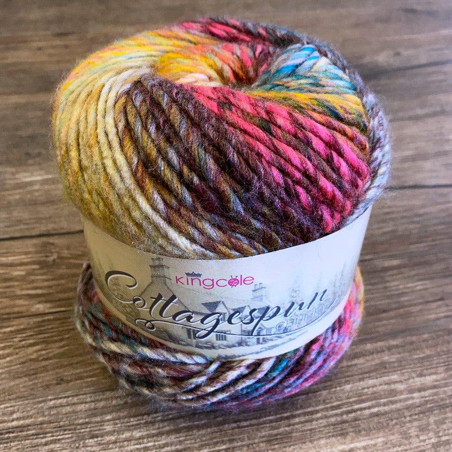 Multicolored ball of yarn with a King Cole label on a wooden surface