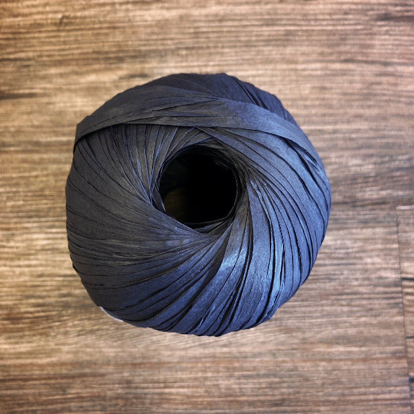 Ball of black paper yarn on a wood background