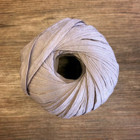 A ball of taupe paper yarn on a wood background