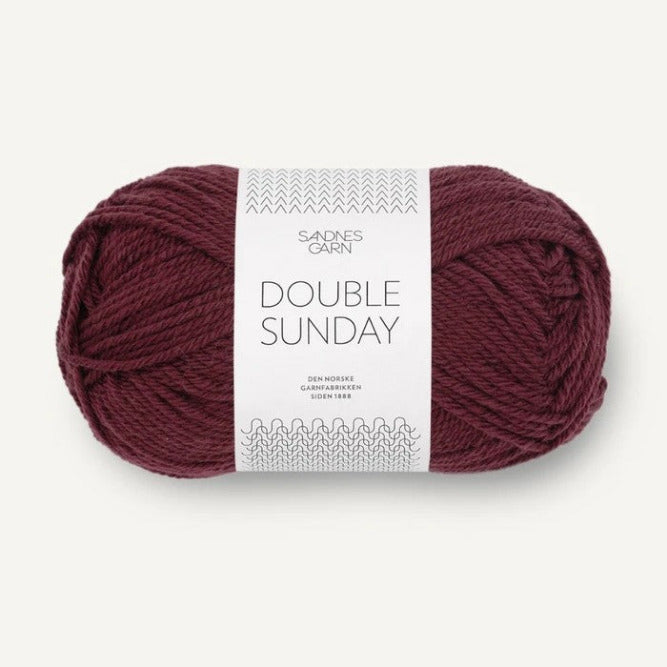 Ball of burgundy yarn with a label on a white background