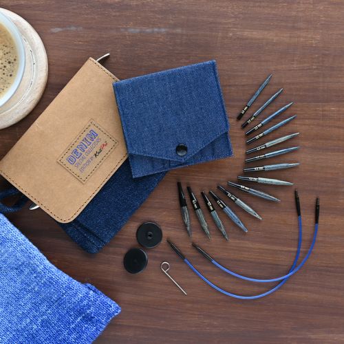 Collection of mini knitting needles, cables, and accessories on a wooden surface