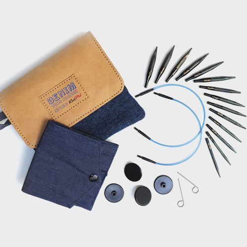 Knitting needle set with denim case and accessories on a light background