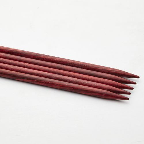 Set of red wooden knitting needles on a white background
