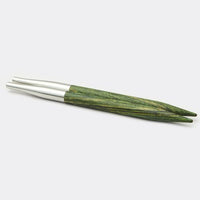 Set of green wooden and silver metal knitting needles on a white background