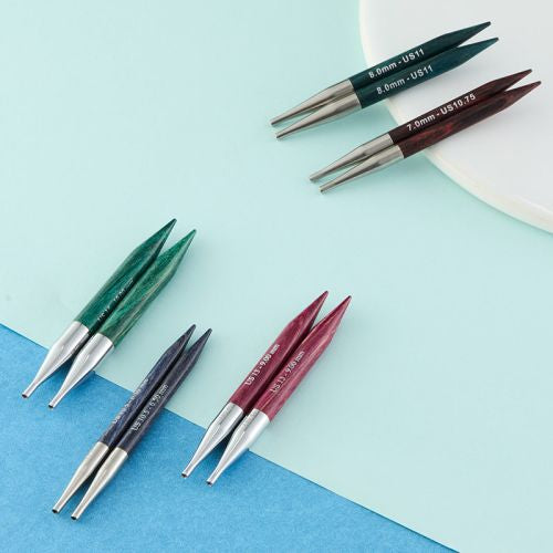 Sets of knitting needles with different sizes on a blue and green background