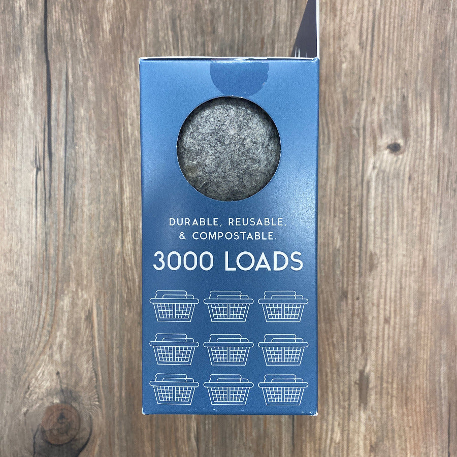 Blue packaging with a circular gray wool ball showing through the packaging, on a wooden surface