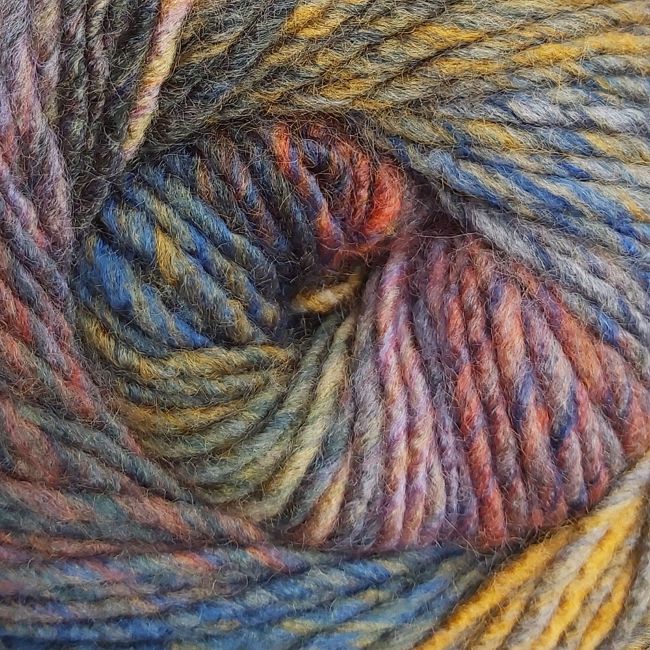 Close-up of a ball of multicolored yarn with shades of blue, mustard, grey, purple, and orange.