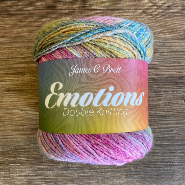 Multicolored skein of yarn with 'James C. Brett Emotions Double Knitting' label on a wooden surface