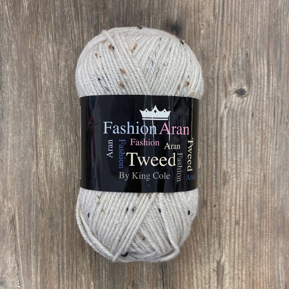 Ball of cream tweed yarn with a King Cole label on a wooden surface