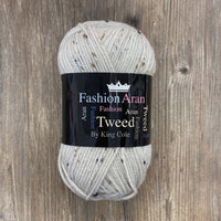 Ball of cream tweed yarn with a King Cole label on a wooden surface