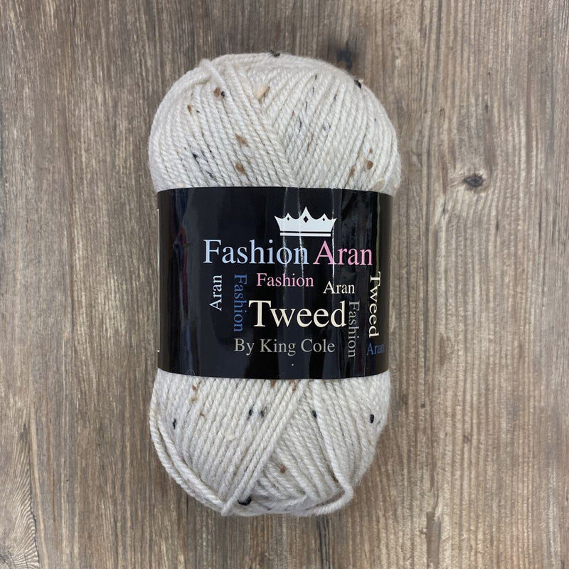 Ball of cream tweed yarn with a King Cole label on a wooden surface