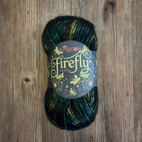A ball of King Cole Firefly Aran yarn, featuring dark green, black, and gold variegated yarn, resting on a rustic wooden surface.