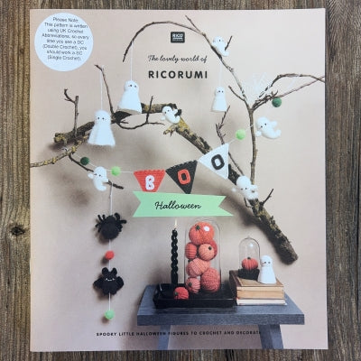 A Halloween crochet book with Ricorumi branding, on a wood background