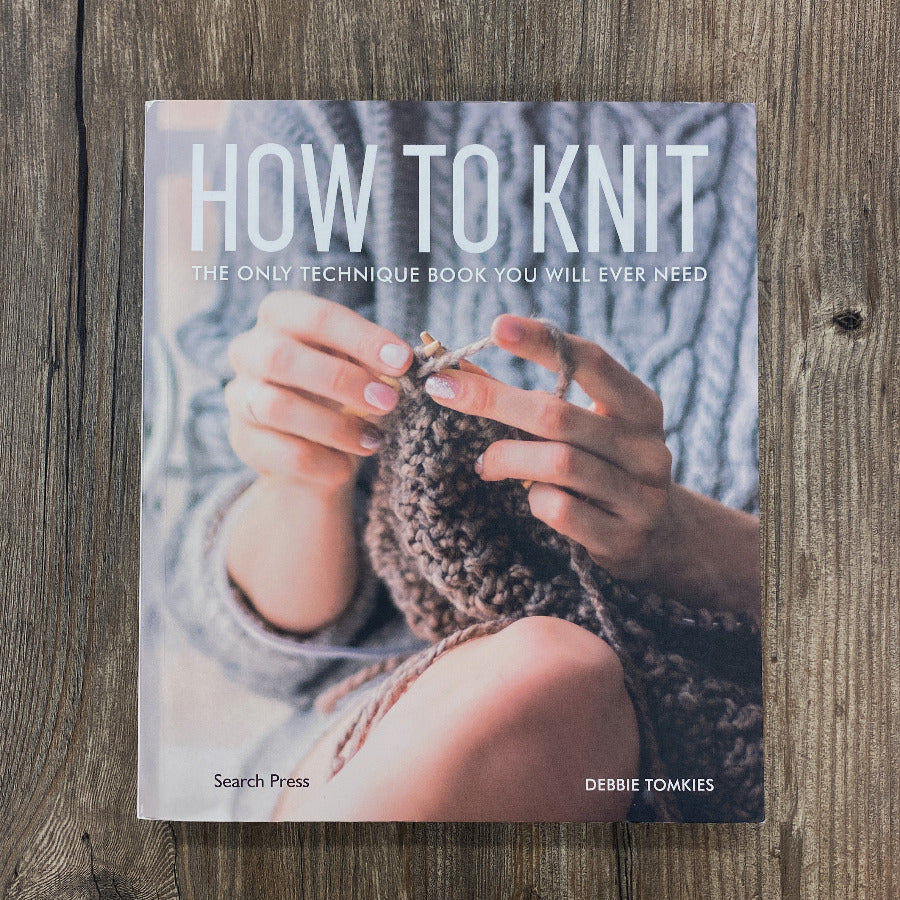 Book titled 'How to Knit' on a wooden surface