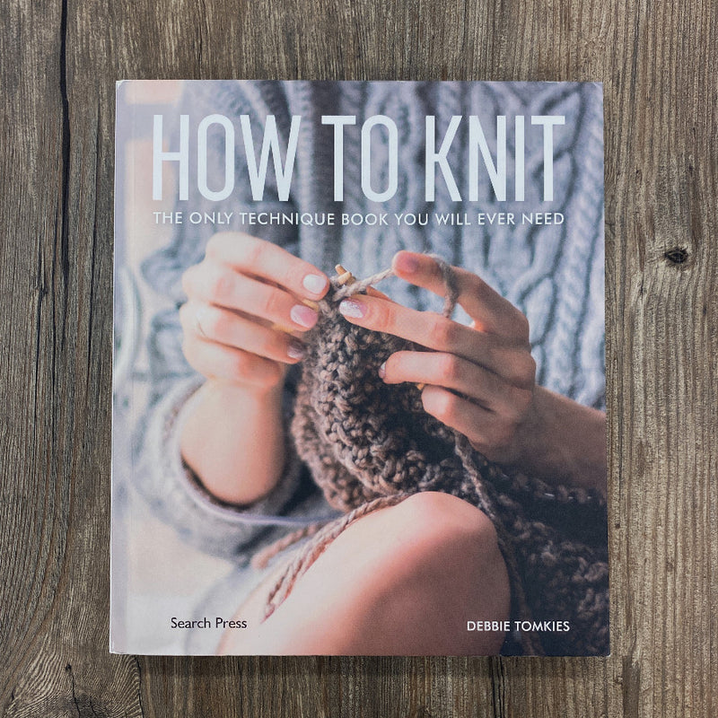Book titled 'How to Knit' on a wooden surface