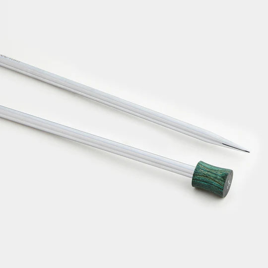 Close up view of shiny silver knitting needles with a green wood end on them on a white background