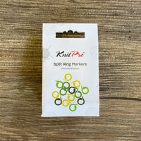 A white box labeled KnitPro Split Ring Markers, with a graphic of green and yellow split ring markers at the bottom, placed on a brown wooden surface.