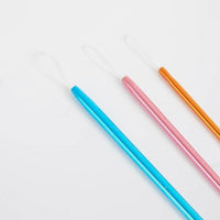 Detail of three colorful wool needles (blue, pink, orange) on a white background