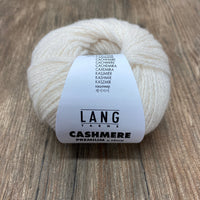 Ball of cream coloured cashmere yarn with a Lang Yarns label on a wooden surface