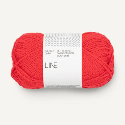 Ball of bright coral orange yarn with a white label on a white background