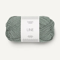 Ball of sage green yarn with a label on a white background
