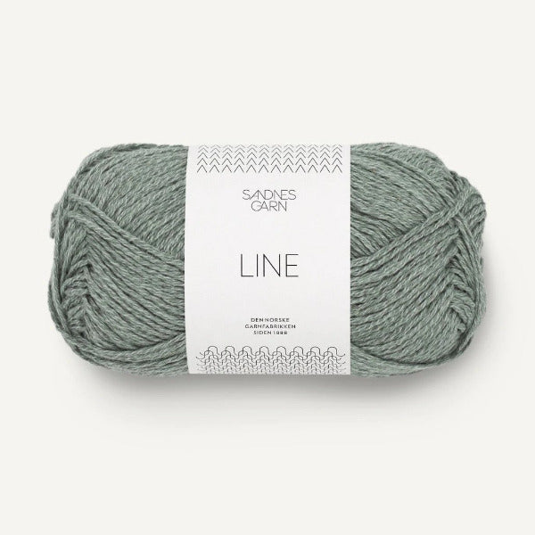 Ball of sage green yarn with a label on a white background