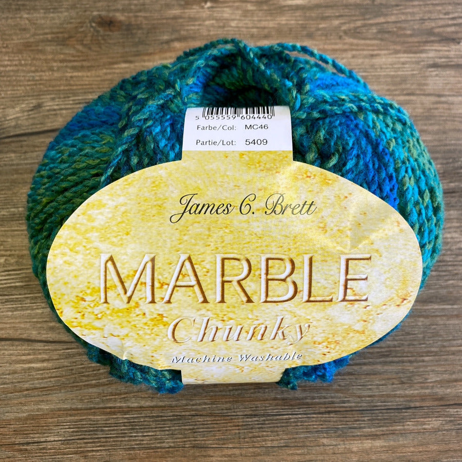 Blue and green skein of yarn with a label on a wooden surface