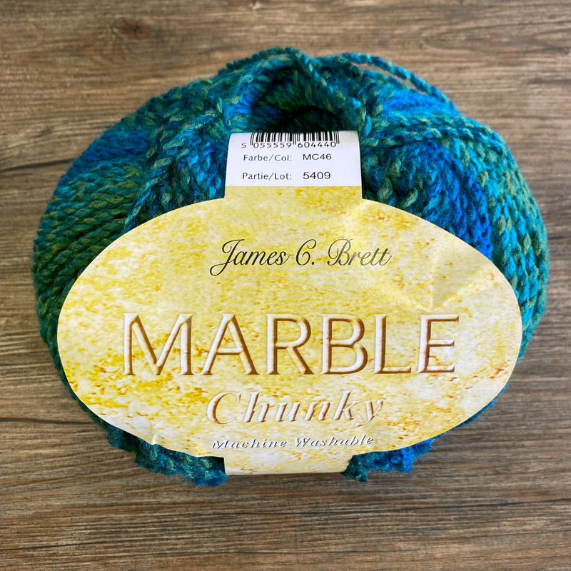 Blue and green skein of yarn with a label on a wooden surface