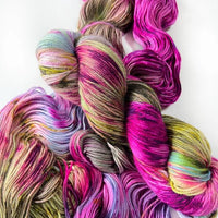Multicolored yarn skeins in pink, green, and purple on a white background