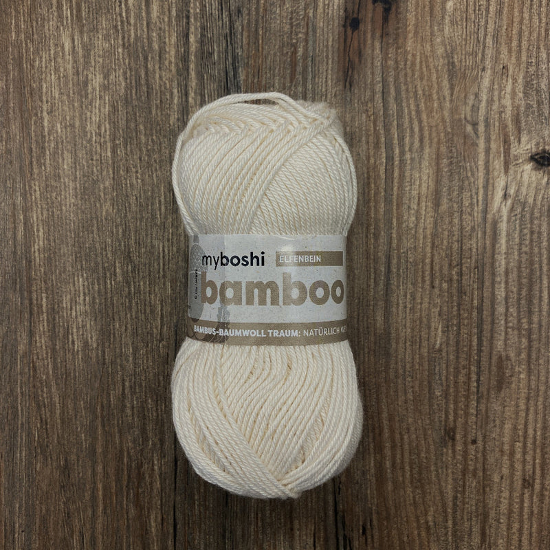 Ball of cream yarn with a label on a wooden background