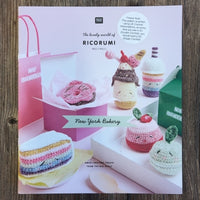 A crocheted food pattern book with Ricorumi branding, on a wood background
