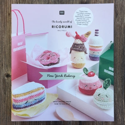A crocheted food pattern book with Ricorumi branding, on a wood background