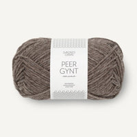 Ball of light brown yarn with a label on a white background