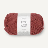 Ball of burnt orange yarn with a label on a white background